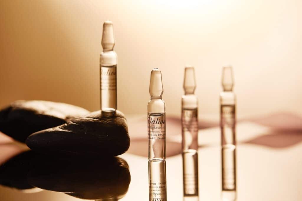 a hand holding a bottle of liquid next to a row of bottles